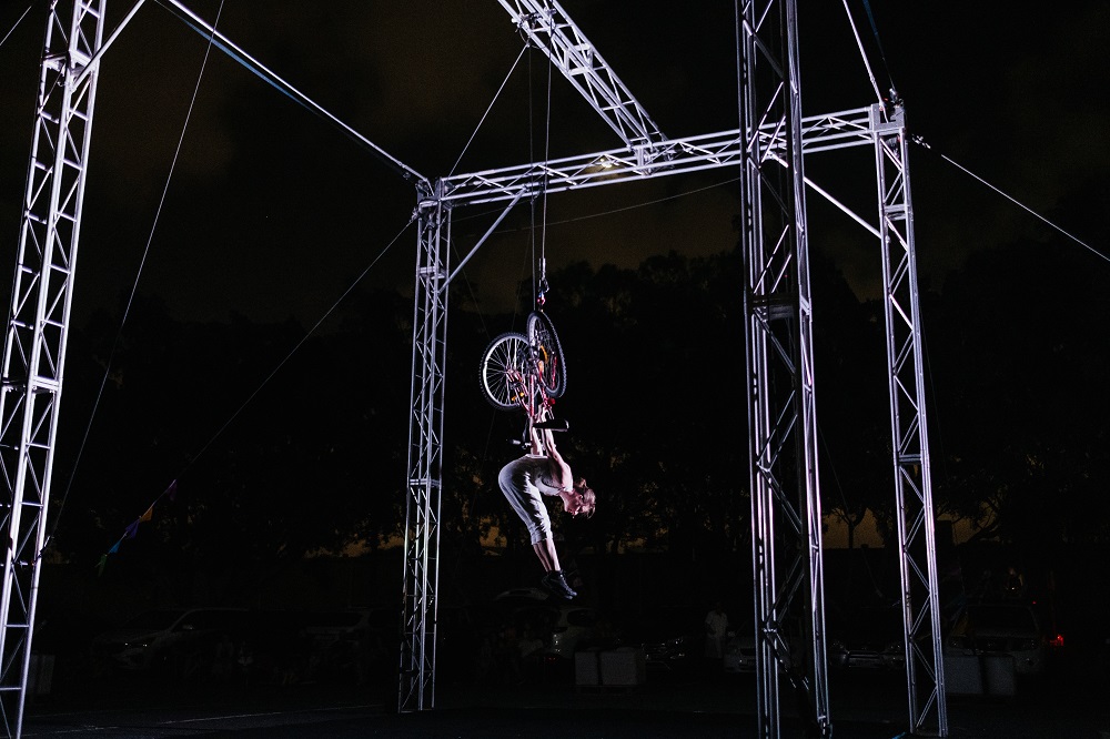 Single performer hanging upside down from scaffold during Rear Vision performance